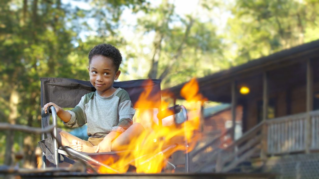 Little boy sitting at a campfire at Drummer Boy Camping Resort
