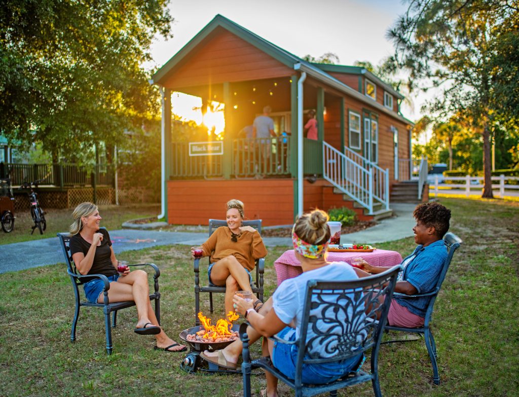 Group of friends sitting around a campfire outside a cabin at Thousand Trails Orlando